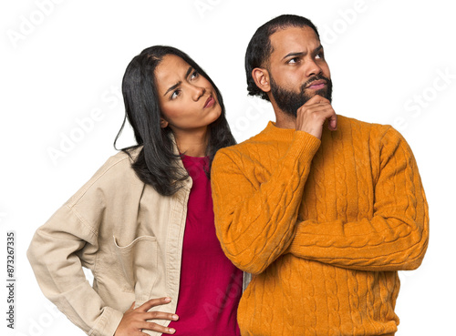 Cuadro en lienzo Young Latino couple in studio thinking and looking up, being reflective, contemplating, having a fantasy