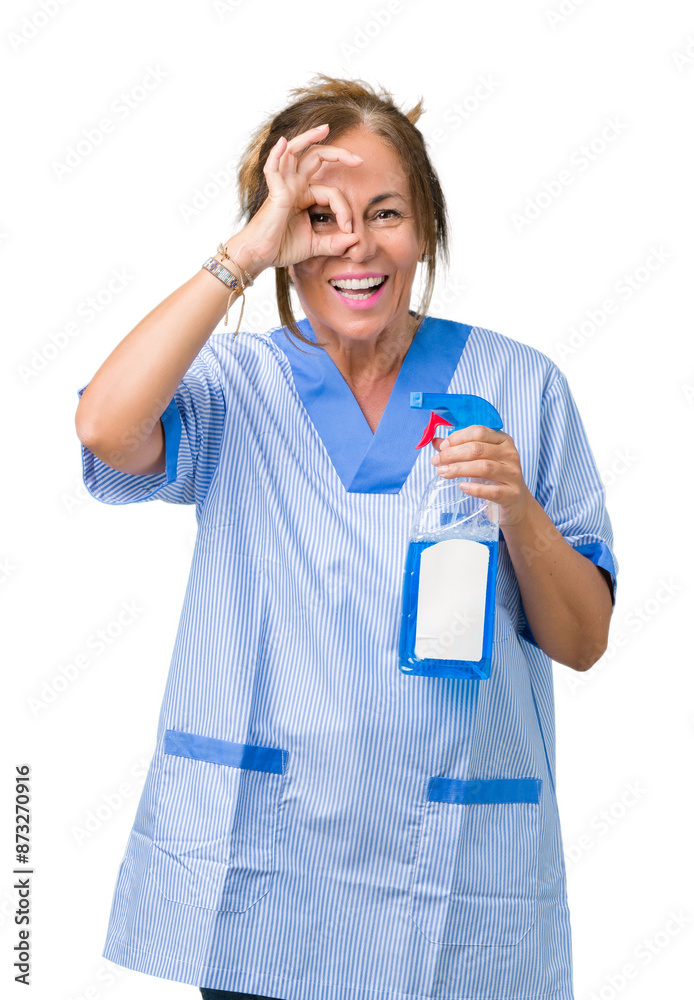 Middle age brunette cleaner woman wearing housework uniform over isolated background with happy face smiling doing ok sign with hand on eye looking through fingers Middle age brunette cleaner woman wearing housework uniform over isolated background with happy face smiling doing ok sign with hand on eye looking through fingers