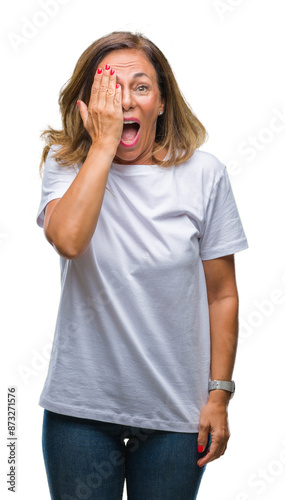 Middle age senior hispanic woman over isolated background covering one eye with hand with confident smile on face and surprise emotion.