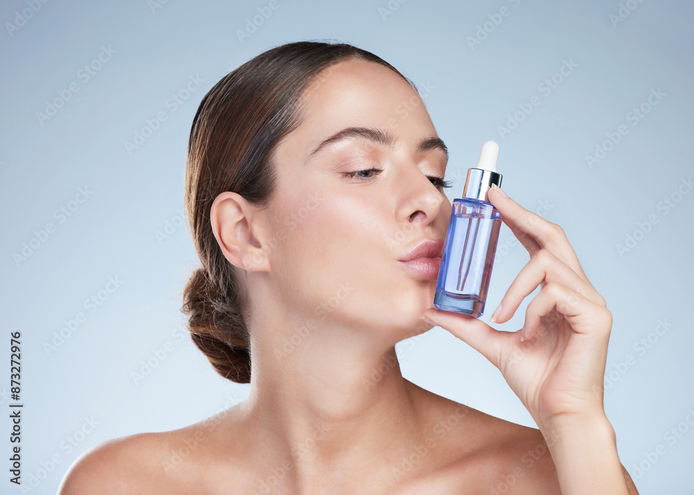 Kiss, skincare and woman with beauty serum in studio, hand and product for glow and vitamin c. Dermatology, shine and bottle for aesthetic, hyaluronic acid and girl in blue background of spa for skin Kiss, skincare and woman with beauty serum in studio, hand and product for glow and vitamin c. Dermatology, shine and bottle for aesthetic, hyaluronic acid and girl in blue background of spa for skin