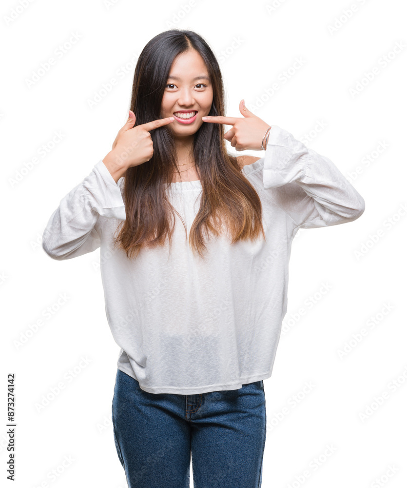 Young asian woman over isolated background smiling confident showing and pointing with fingers teeth and mouth. Health concept. Young asian woman over isolated background smiling confident showing and pointing with fingers teeth and mouth. Health concept.