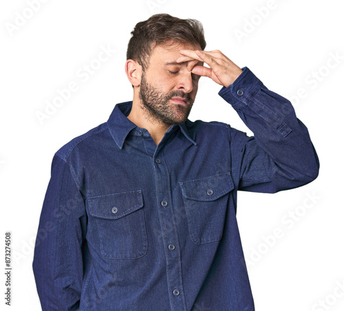 Studio portrait of young Hispanic male having a head ache, touching front of the face.