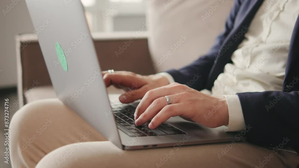 Curly focused business man in a jacket and pajama pants working on laptop sitting at home office sofa Curly focused business man in a jacket and pajama pants working on laptop sitting at home office sofa