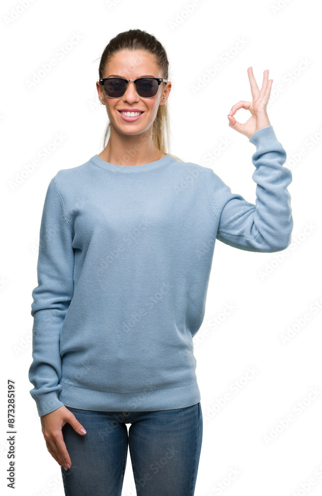 Beautiful young woman wearing sunglasses and ponytail doing ok sign with fingers, excellent symbol