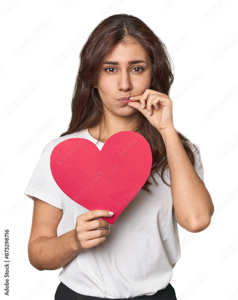 Middle Eastern woman holding paper heart with fingers on lips keeping a secret. Middle Eastern woman holding paper heart with fingers on lips keeping a secret.