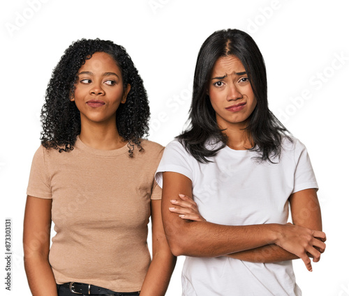 Young Latin friends in studio unhappy looking in camera with sarcastic expression.