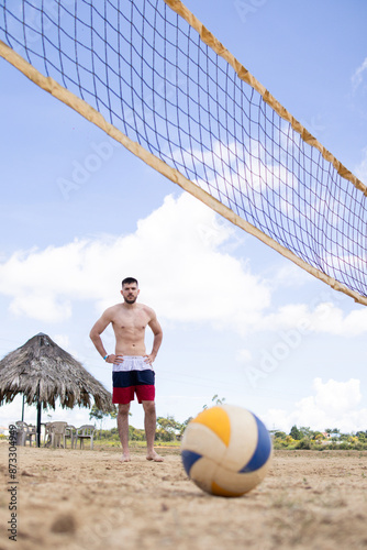 shirtless fit white man playing volleyball on a beach