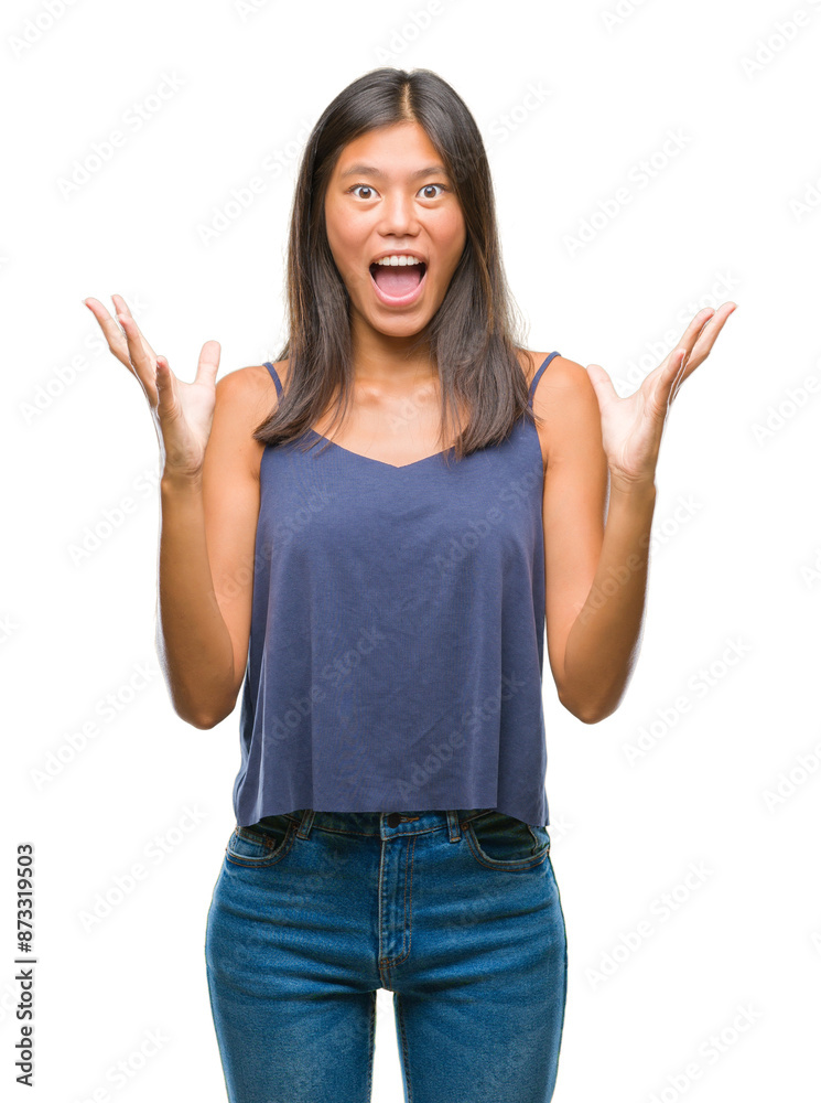 Young asian woman over isolated background celebrating crazy and amazed for success with arms raised and open eyes screaming excited. Winner concept