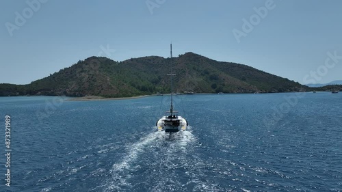 Aerial view of a moored yacht boat in beautiful calm sea bay with turquoise water near Fethiye, Turkey. Full circle around luxury