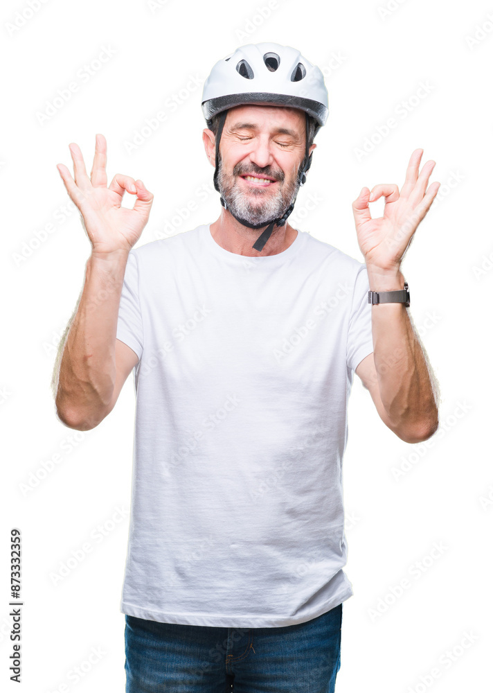 Middle age senior hoary cyclist man wearing bike safety helment isolated background relax and smiling with eyes closed doing meditation gesture with fingers. Yoga concept.