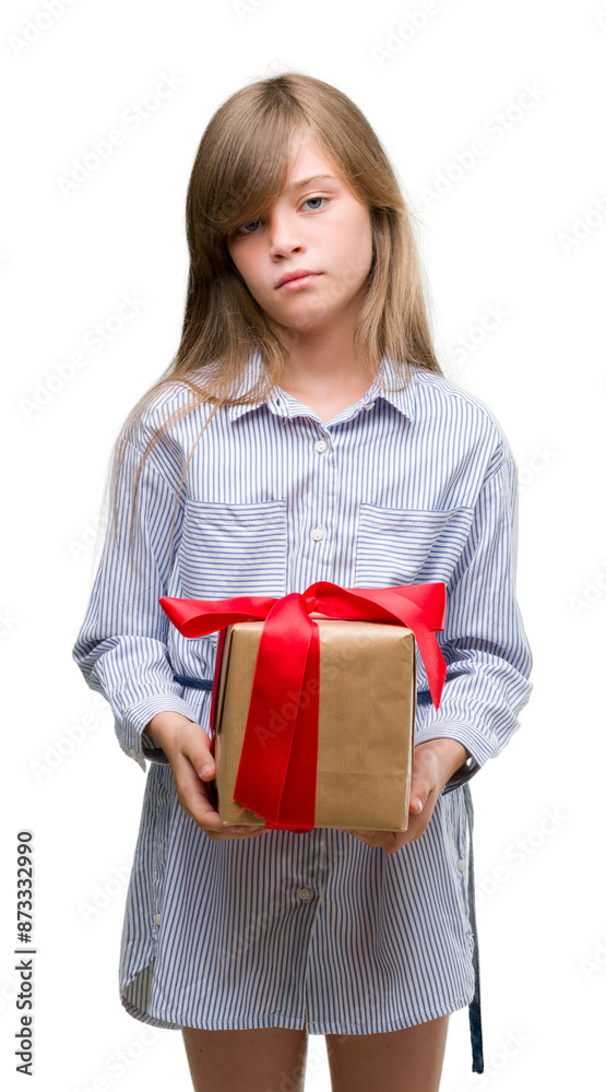 Young blonde toddler holding a present with a confident expression on smart face thinking serious Young blonde toddler holding a present with a confident expression on smart face thinking serious