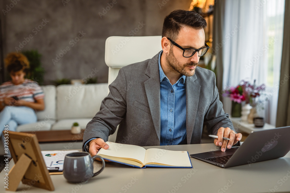 Adult man work from home on laptop whit girlfriend in the background