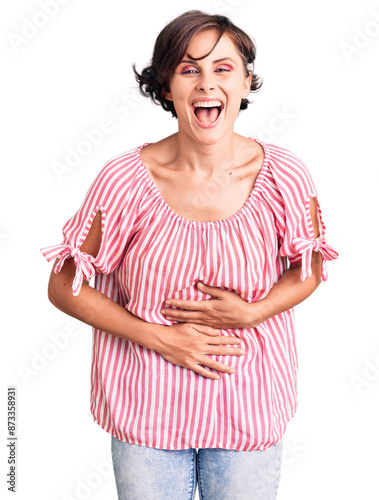 Beautiful young woman with short hair wearing casual summer clothes smiling and laughing hard out loud because funny crazy joke with hands on body.