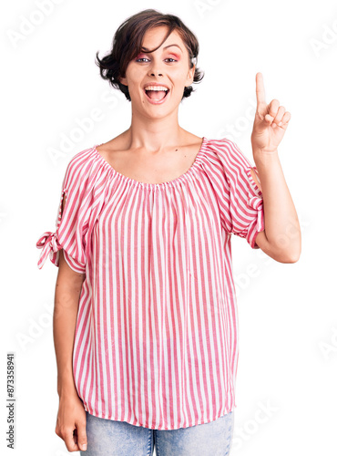Beautiful young woman with short hair wearing casual summer clothes showing and pointing up with finger number one while smiling confident and happy.