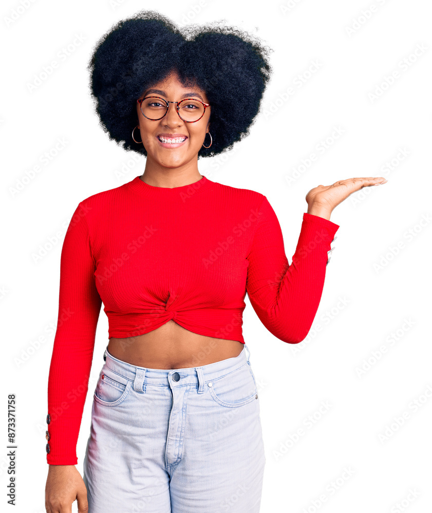 Young african american girl wearing casual clothes and glasses smiling cheerful presenting and pointing with palm of hand looking at the camera. Young african american girl wearing casual clothes and glasses smiling cheerful presenting and pointing with palm of hand looking at the camera.
