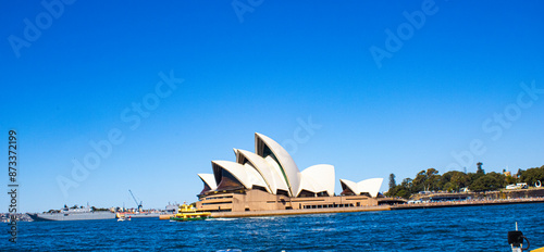 Iconic Sydney Opera House against a serene seascape, adorned with a vibrant yellow boat. A breathtaking blend of architecture and maritime beauty in New South Wales, Australia. photo