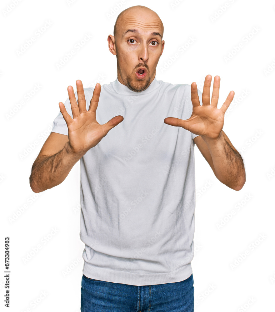 Bald man with beard wearing casual white t shirt afraid and terrified with fear expression stop gesture with hands, shouting in shock. panic concept. Bald man with beard wearing casual white t shirt afraid and terrified with fear expression stop gesture with hands, shouting in shock. panic concept.