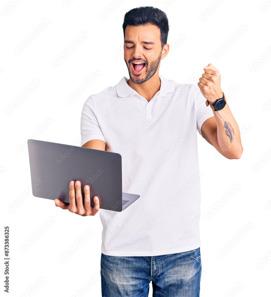 Young handsome hispanic man working using computer laptop screaming proud, celebrating victory and success very excited with raised arms Young handsome hispanic man working using computer laptop screaming proud, celebrating victory and success very excited with raised arms