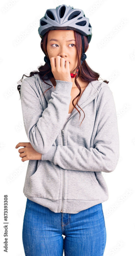Young beautiful chinese girl wearing bike helmet looking stressed and nervous with hands on mouth biting nails. anxiety problem. Young beautiful chinese girl wearing bike helmet looking stressed and nervous with hands on mouth biting nails. anxiety problem.