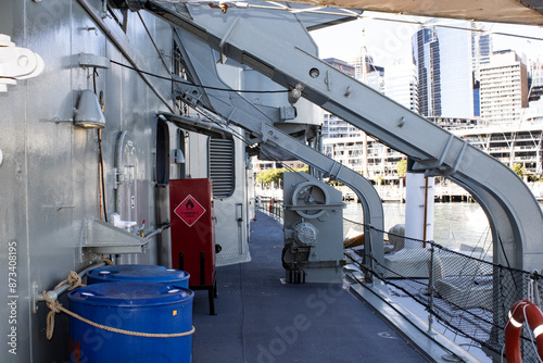 A stunning daylight shot capturing the intricate details of a ship's metallic deck, set against the backdrop of majestic Australian naval warships and beautiful architectural structures.
