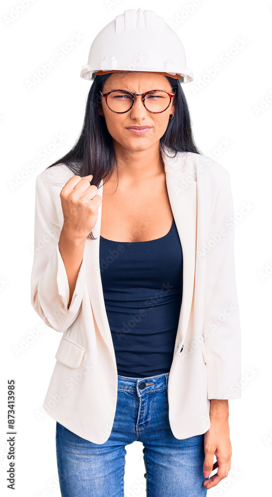 Young beautiful latin girl wearing architect hardhat and glasses angry and mad raising fist frustrated and furious while shouting with anger. rage and aggressive concept. Young beautiful latin girl wearing architect hardhat and glasses angry and mad raising fist frustrated and furious while shouting with anger. rage and aggressive concept.