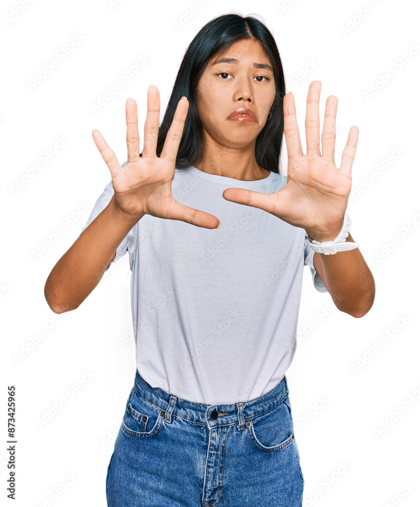 Beautiful young asian woman wearing casual white t shirt afraid and terrified with fear expression stop gesture with hands, shouting in shock. panic concept. Beautiful young asian woman wearing casual white t shirt afraid and terrified with fear expression stop gesture with hands, shouting in shock. panic concept.