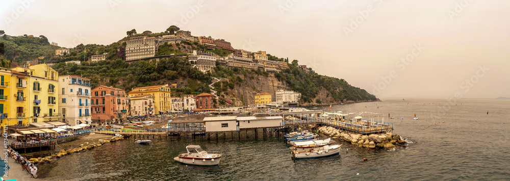Sorrento, Italy - July 24, 2024: Wide angle view of Sorrento town showing boats, deck, coast, buildings and tourists