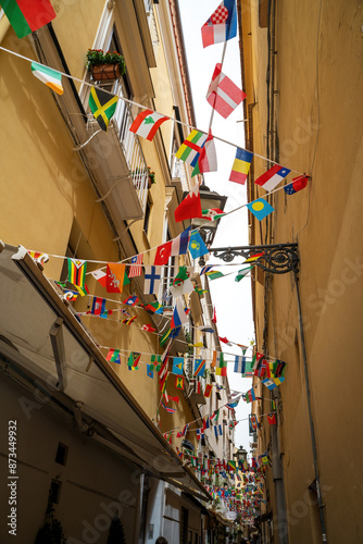 Obraz na płótnie Sorrento, Italy - June 24, 2024: Narrow streets of Sorrento with shops and flags of different countries hanging on a rope w salonie