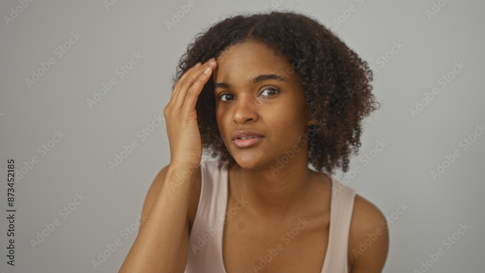 Beautiful young african american woman with curly hair touching her head over isolated white background. Beautiful young african american woman with curly hair touching her head over isolated white background.