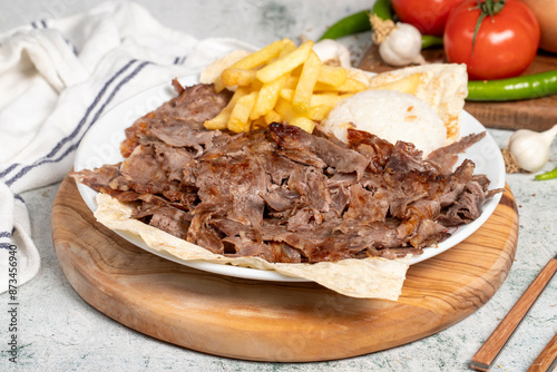 Meat doner with rice and French fries. Traditional Turkish cuisine taste. Meat doner kebab over rice cooked on a gray background. local name pilavustu et doner. Close up