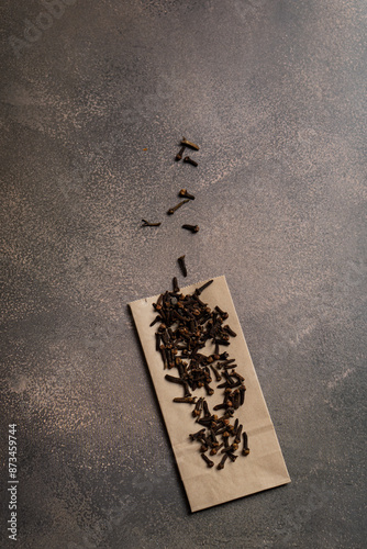 Dried cloves spices and a fabric bag lie on a dark gray background