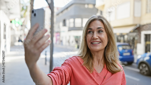 Smiling middle-aged caucasian woman taking a selfie outdoors on a city street Free Download Smiling middle-aged caucasian woman taking a selfie outdoors on a city street - GFXLoad