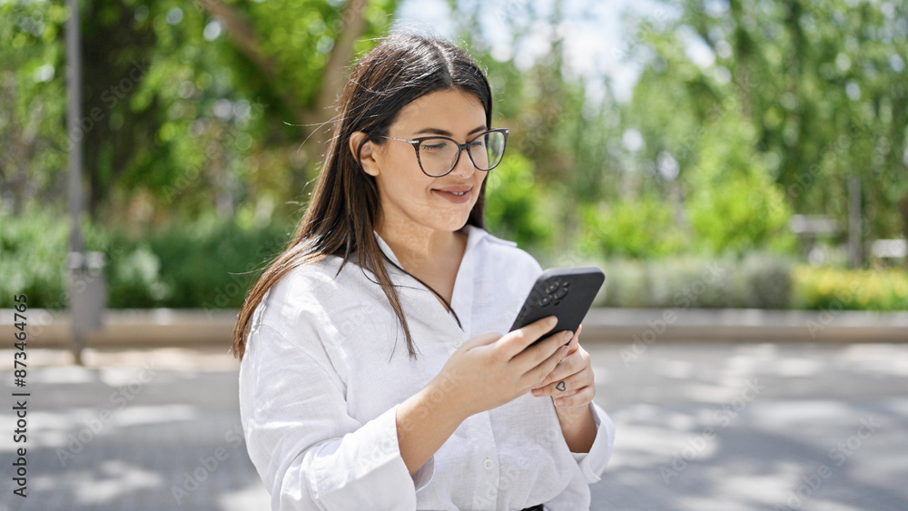 Young beautiful hispanic woman smiling happy using smartphone in the streets of Madrid Young beautiful hispanic woman smiling happy using smartphone in the streets of Madrid