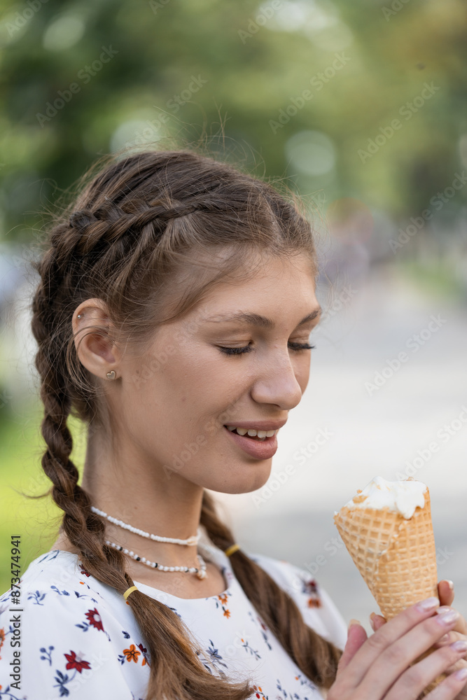a young girl on a city street on a sunny summer day walks and eats ice cream a young girl on a city street on a sunny summer day walks and eats ice cream