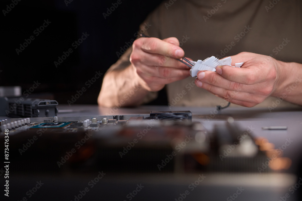 A technician is skillfully repairing a computer GPU fan with precision tools in a workshop A technician is skillfully repairing a computer GPU fan with precision tools in a workshop