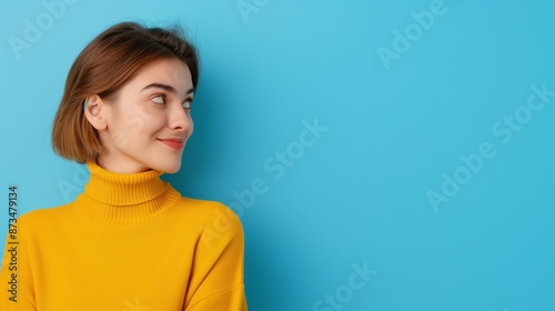 A woman in a yellow sweater is looking at the camera with a smile on her face. Concept of warmth and happiness, as the woman is enjoying her time