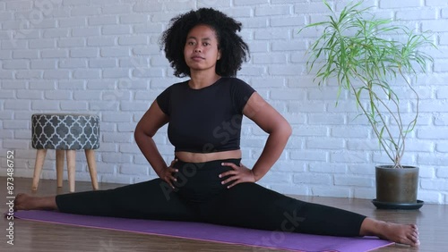 Athletic woman demonstrates stretching in splits on yoga mat. Deep stretching female improves flexibility and health body Regular stretching can help achieve impressive fitness results for flexibility