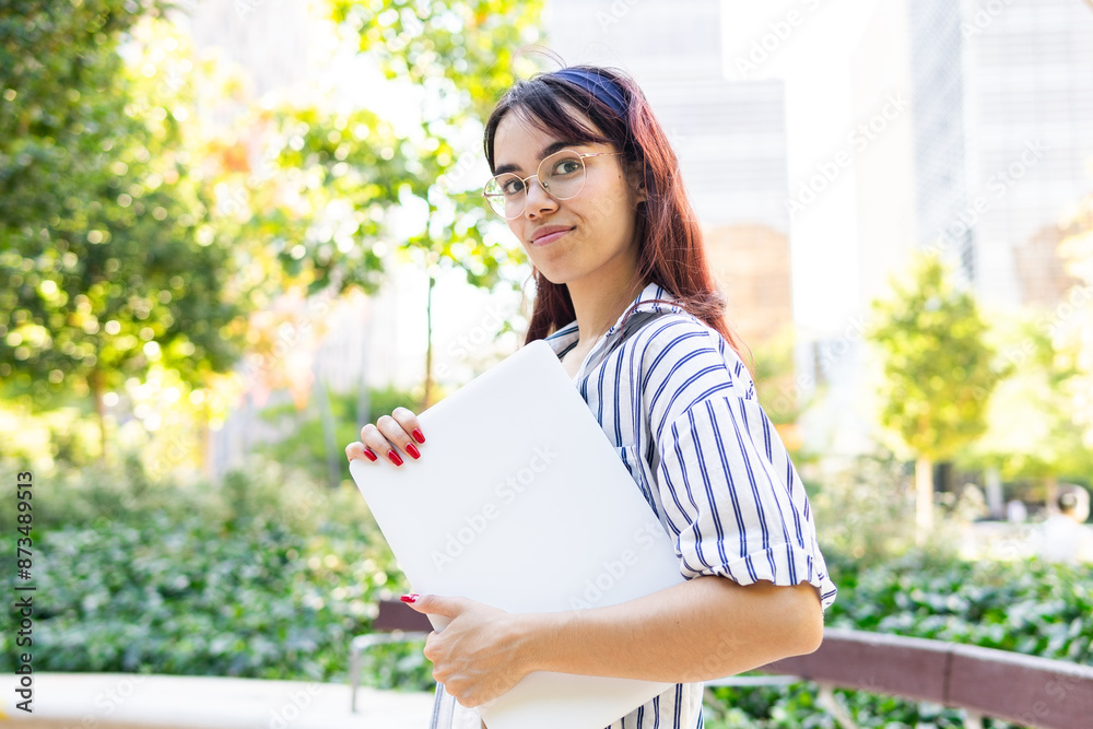 Young woman with laptop in lush urban park setting Young woman with laptop in lush urban park setting