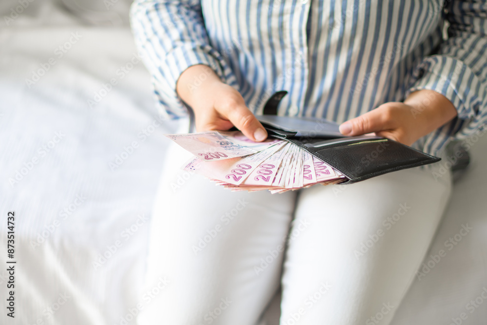 Leather wallet with money in the hands of a woman. Close-up of a woman taking a Turkish lira with a fan from her wallet, a lot of money but little value,high inflation rate in Turkey Leather wallet with money in the hands of a woman. Close-up of a woman taking a Turkish lira with a fan from her wallet, a lot of money but little value,high inflation rate in Turkey