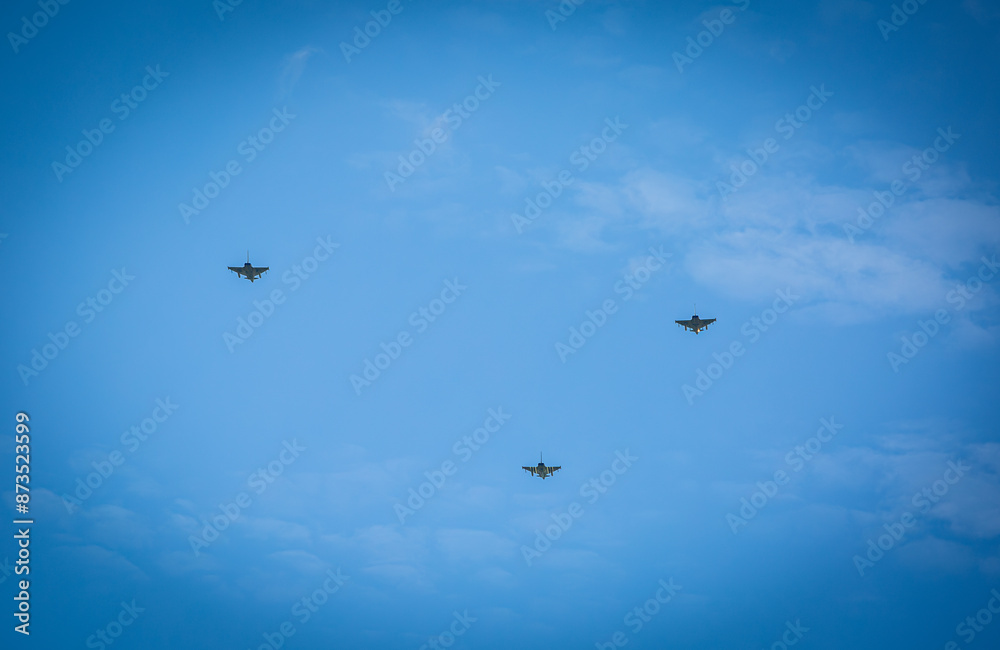 Three RAF typhoons flying, flying in formation back to their respected air fields after taking part in the kings fly past on a beautiful summers day with blue skies and slight cloud Three RAF typhoons flying, flying in formation back to their respected air fields after taking part in the kings fly past on a beautiful summers day with blue skies and slight cloud