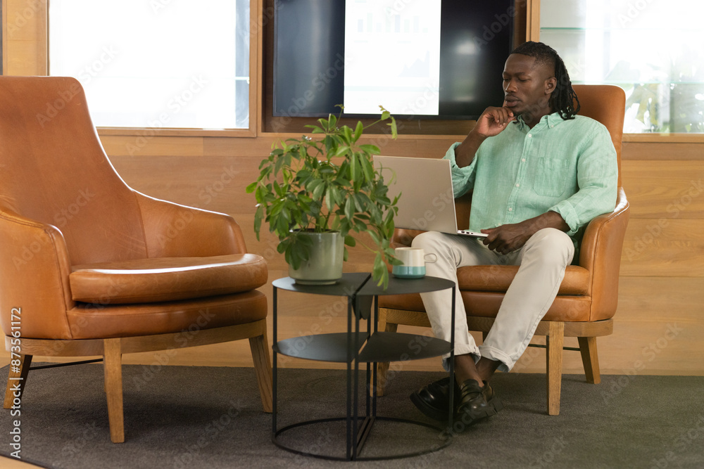Working in modern office, man using laptop and sitting on leather chair Working in modern office, man using laptop and sitting on leather chair