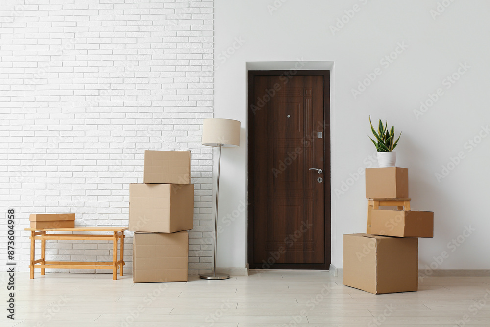 Cardboard boxes with lamp near door in room on moving day Cardboard boxes with lamp near door in room on moving day
