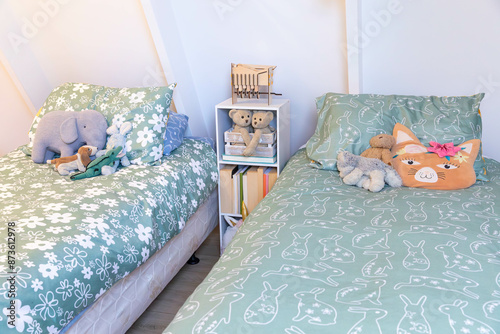 Green coordinated girls bedroom with two beds, toys, books and a technology free zone.