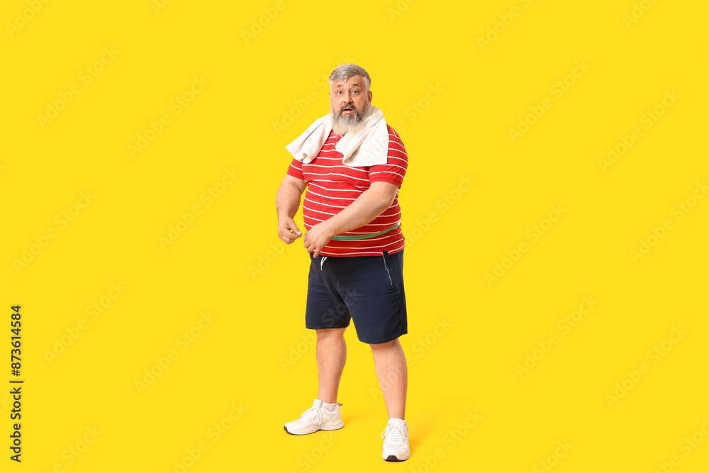 Overweight shocked mature man with measuring tape on yellow background. Weight loss concept Overweight shocked mature man with measuring tape on yellow background. Weight loss concept