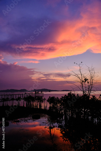 Golden hues of sunset paint the sky and reflect on the tranquil waters, creating a serene and picturesque scene by the pier
