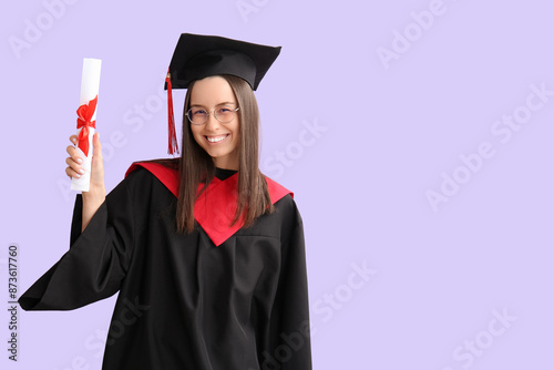 Young female graduate with diploma on lilac background