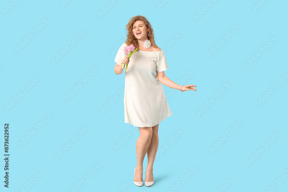 Happy young woman in stylish white dress with beautiful flowers on blue background Happy young woman in stylish white dress with beautiful flowers on blue background
