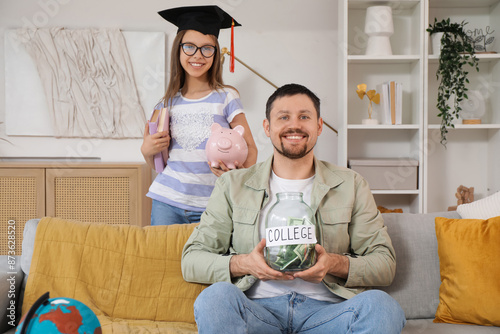 Father and his daughter with piggy bank and money jar at home. Tuition fees c...