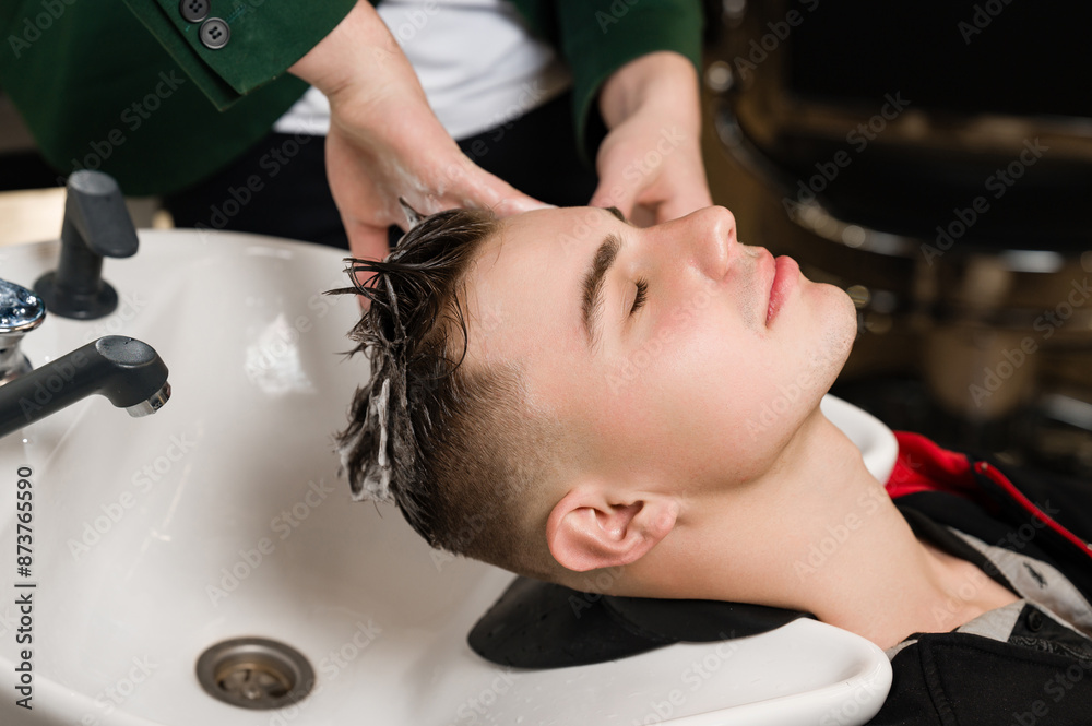 Fototapeta premium Barber shampooing washing a male clients head in the sink.