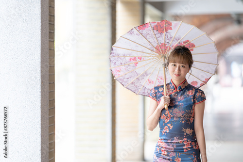 Young Taiwanese woman in her 20s wearing a blue cheongsam, strolling through a cultural district in Wanhua, Taipei, Taiwan, while holding a Chinese-patterned umbrella photo